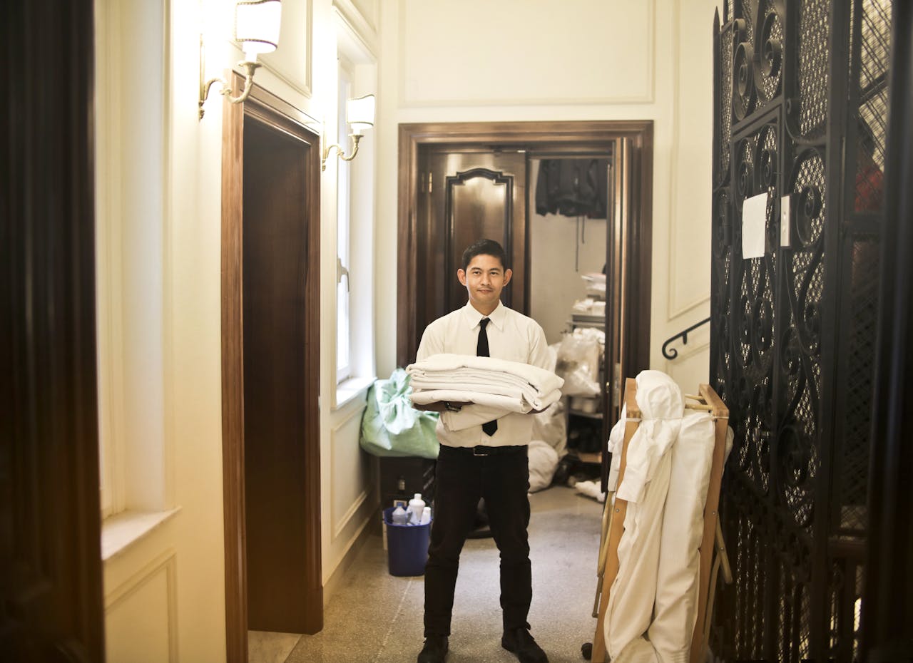 Home Professional hotel staff member carrying fresh linens in an elegant hallway.
